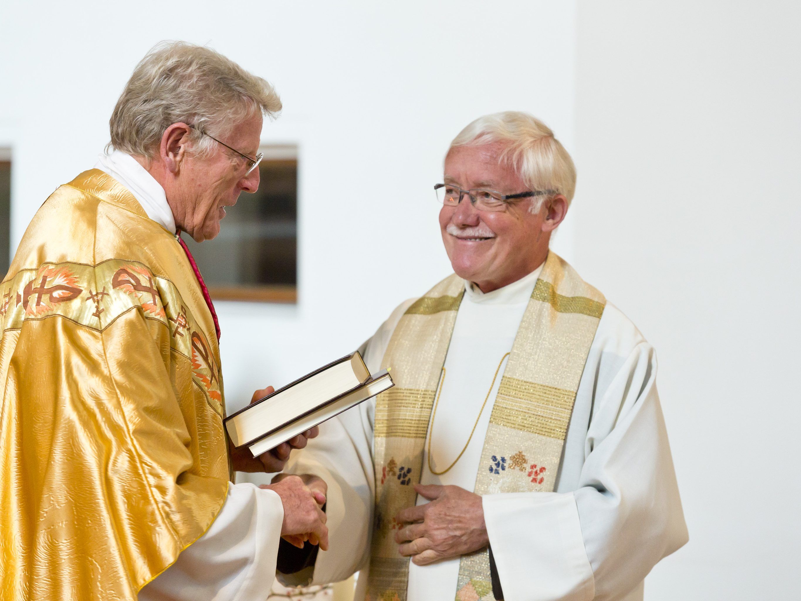 Bruder Erich Geir, Provinzial (Ordensoberer) der Kapuziner Österreichs und Südtirols (li) übergibt dem neuen Guardian Bruder Karl-Martin Gort die Satzungen der Kapuziner, symbolhaft für das Leitungsamt.