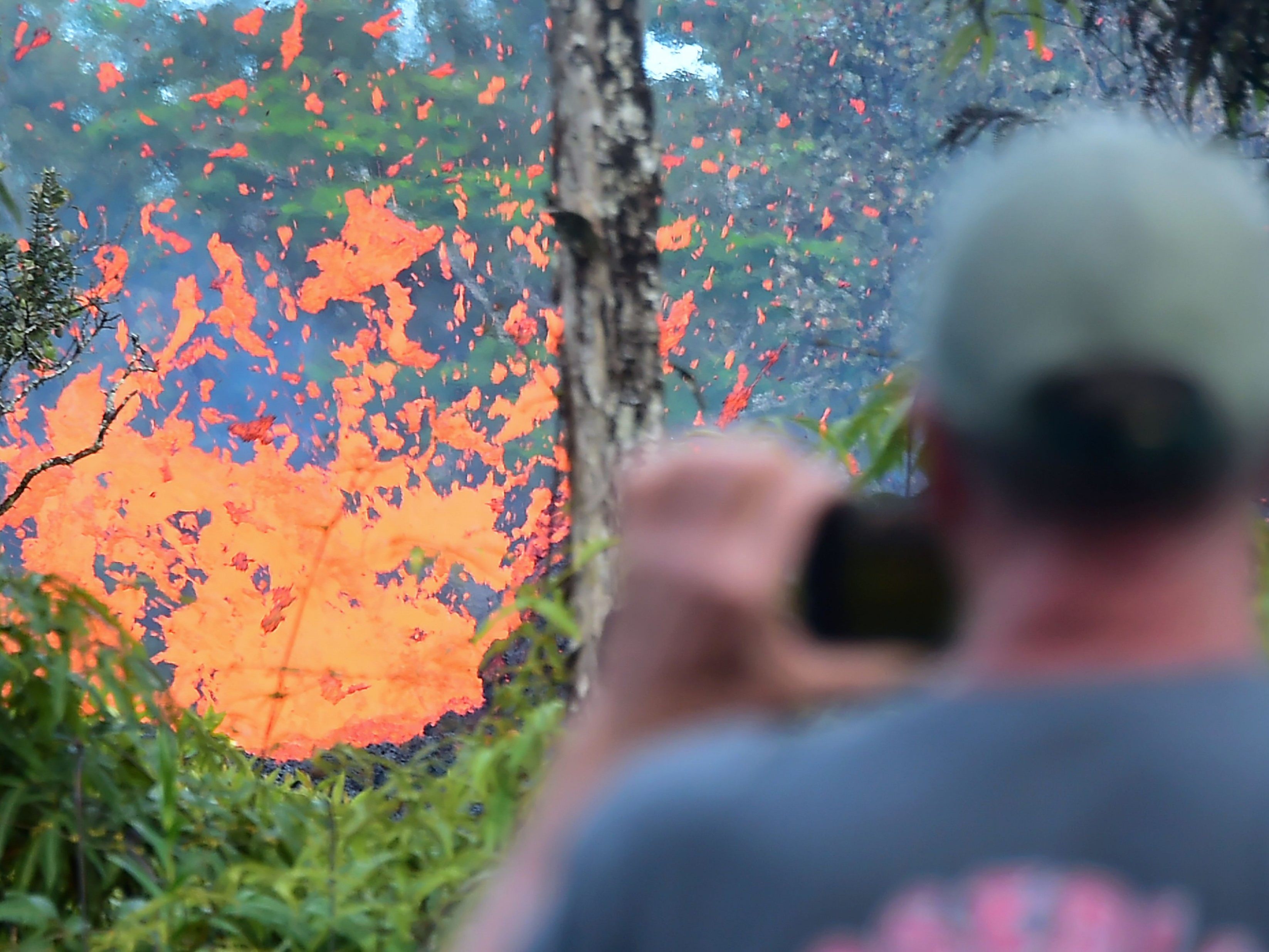 Ein Mann beobachtet Lava, die aus einer Erdspalte bricht..