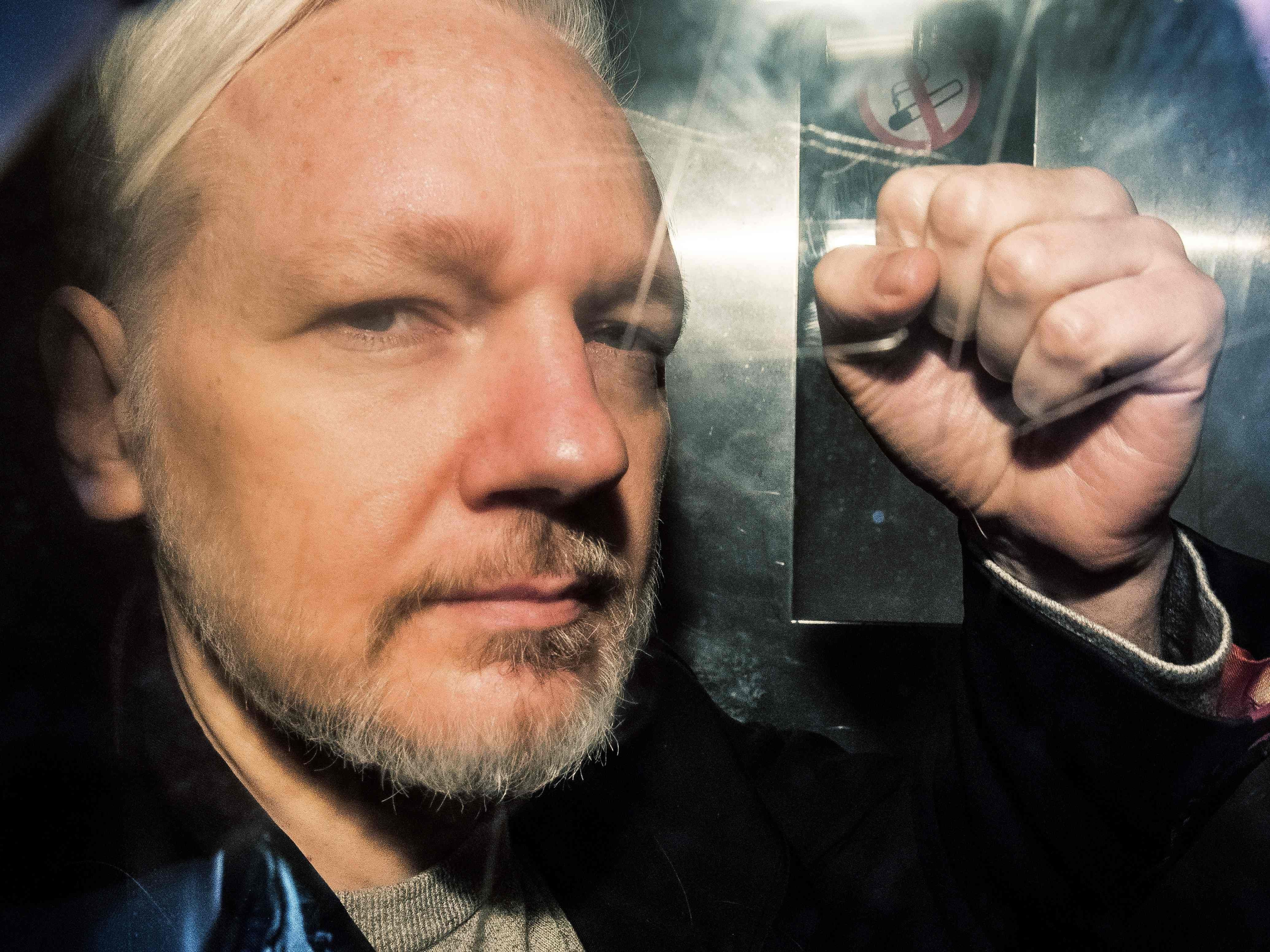 Wikileaks-Gründer Julian Assange gestikuliert aus dem Fenster eines Gefängnis-Busses