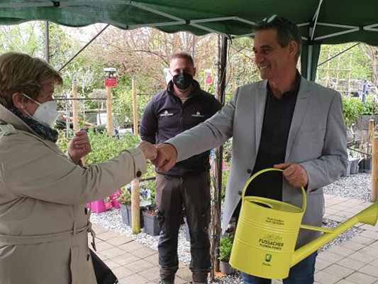 Bürgermeister Peter Böhler übergibt eine Gießkanne an Blumentrogpatin Christine Pratzer.