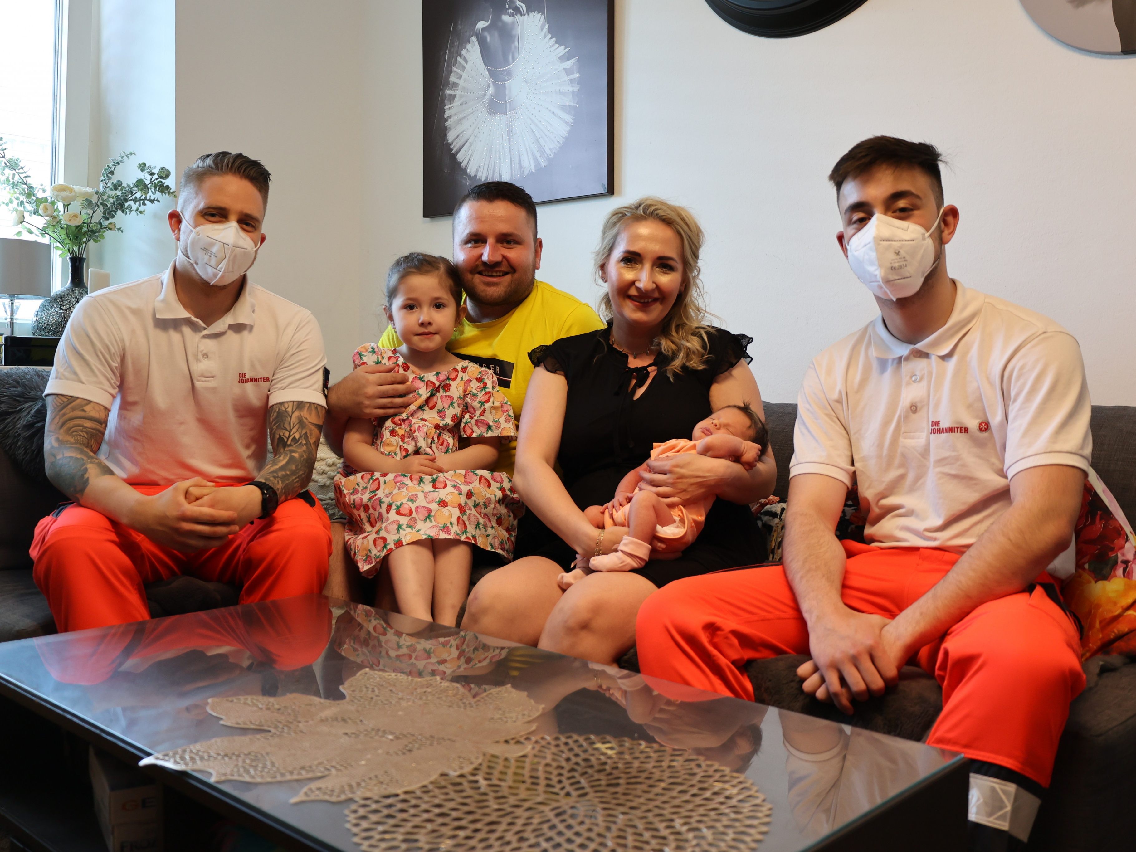 Die nun vierköpfige Familie mit den beiden Sanitätern.