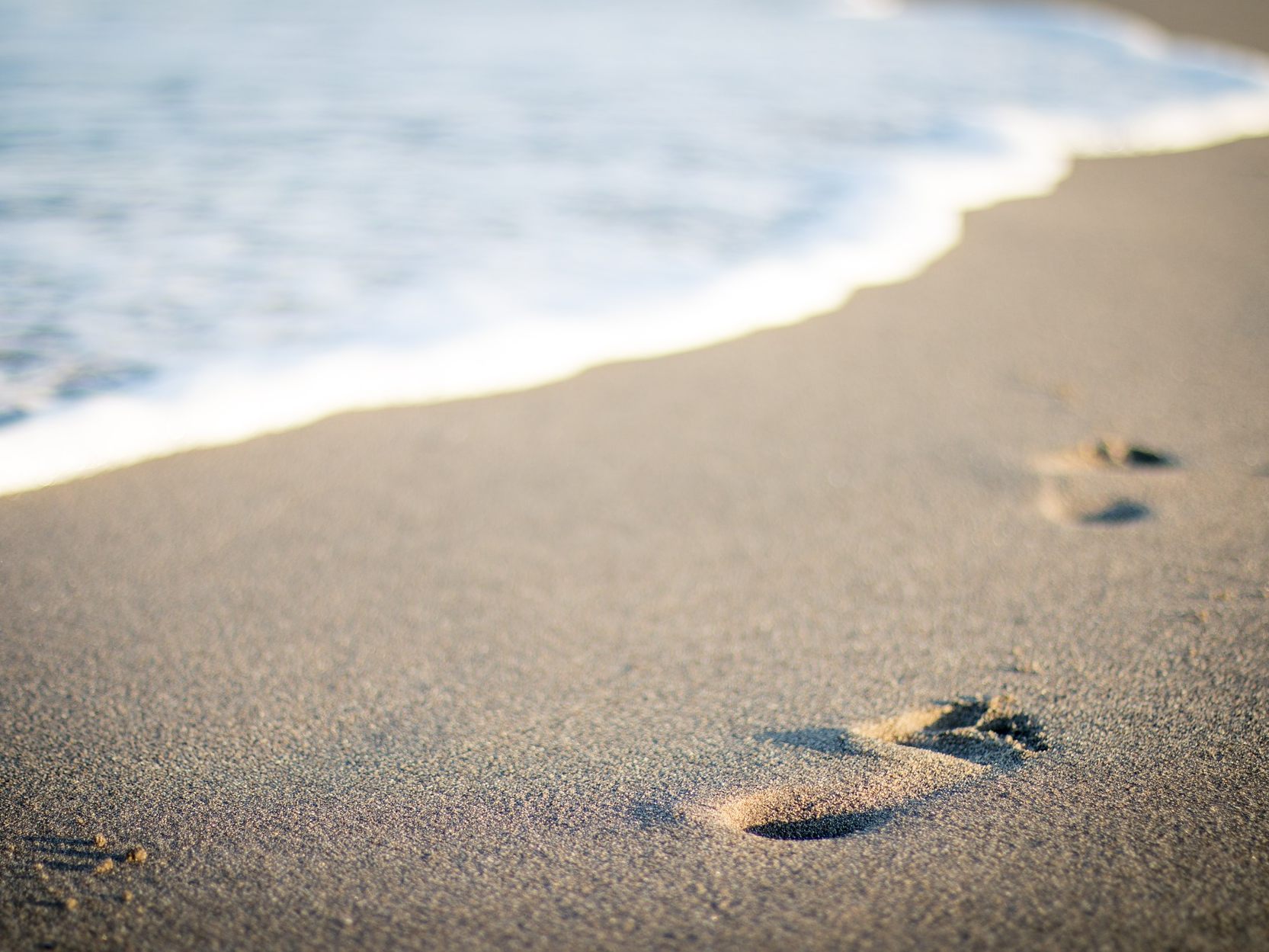 Symbolfoto eines Sandstrandes mit Fußabdrücken. Symbolfoto eines Sandstrandes mit Fußabdrücken.