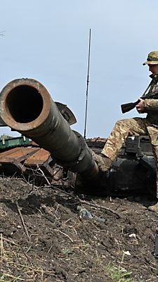 Ukrainischer Soldat betrachtet russisches Panzerwrack