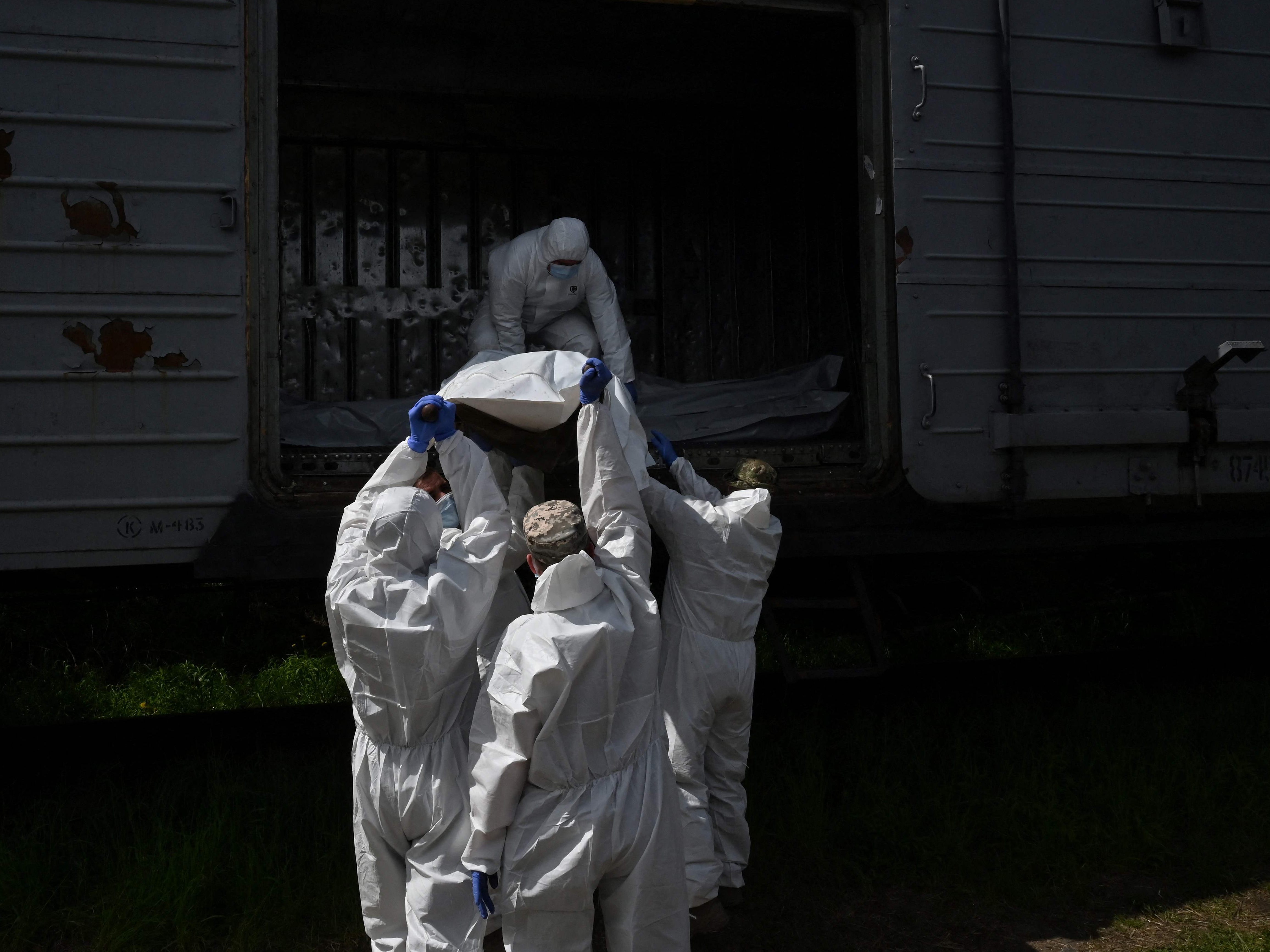 Ukrainische Forensiker untersuchen den Leichnam eines russischen Soldaten in einem Kühltransporter voll mit toten russischen Soldaten. Ukrainische Forensiker untersuchen den Leichnam eines russischen Soldaten in einem Kühltransporter voll mit toten russischen Soldaten.