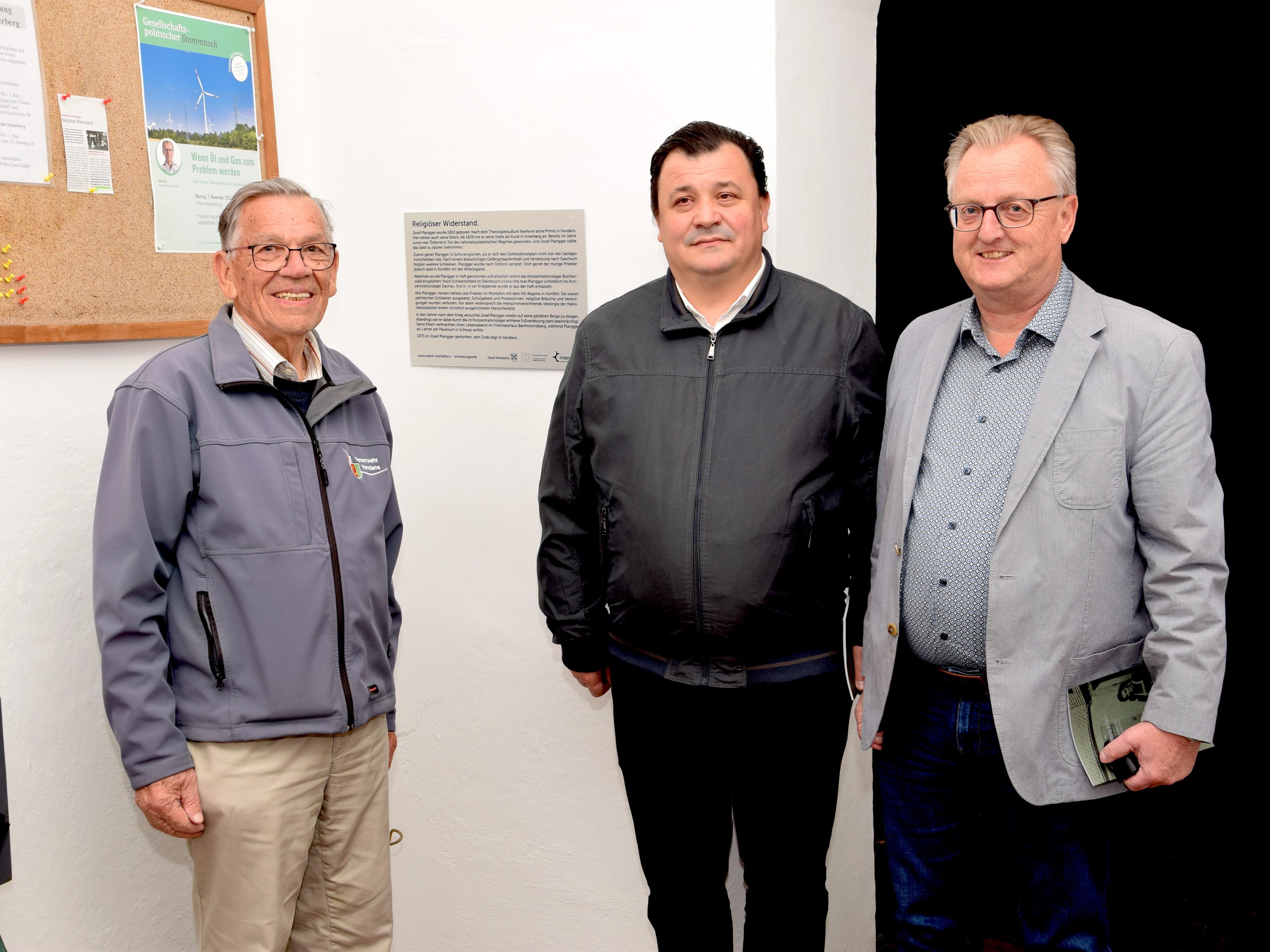 Diakon Rudolf Sagmeister aus Vandans, Pfarrer Celestin Disca Lucaci und Bgm. Martin Vallaster (beide Bartholomäberg) vor dem Erinnerungszeichen "In memoriam Josef Plangger" im Vorzeichen der Innerberger Kirche.