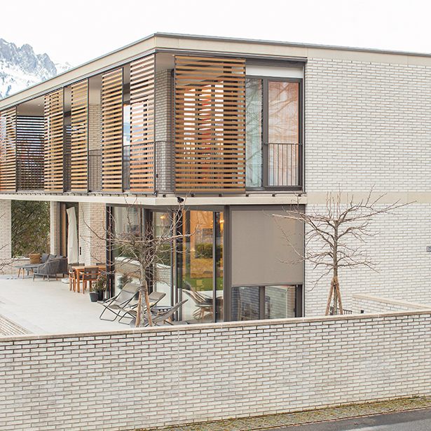 Heller Klinker, schattenspendende Holzlamellen, viel Raum und Licht.