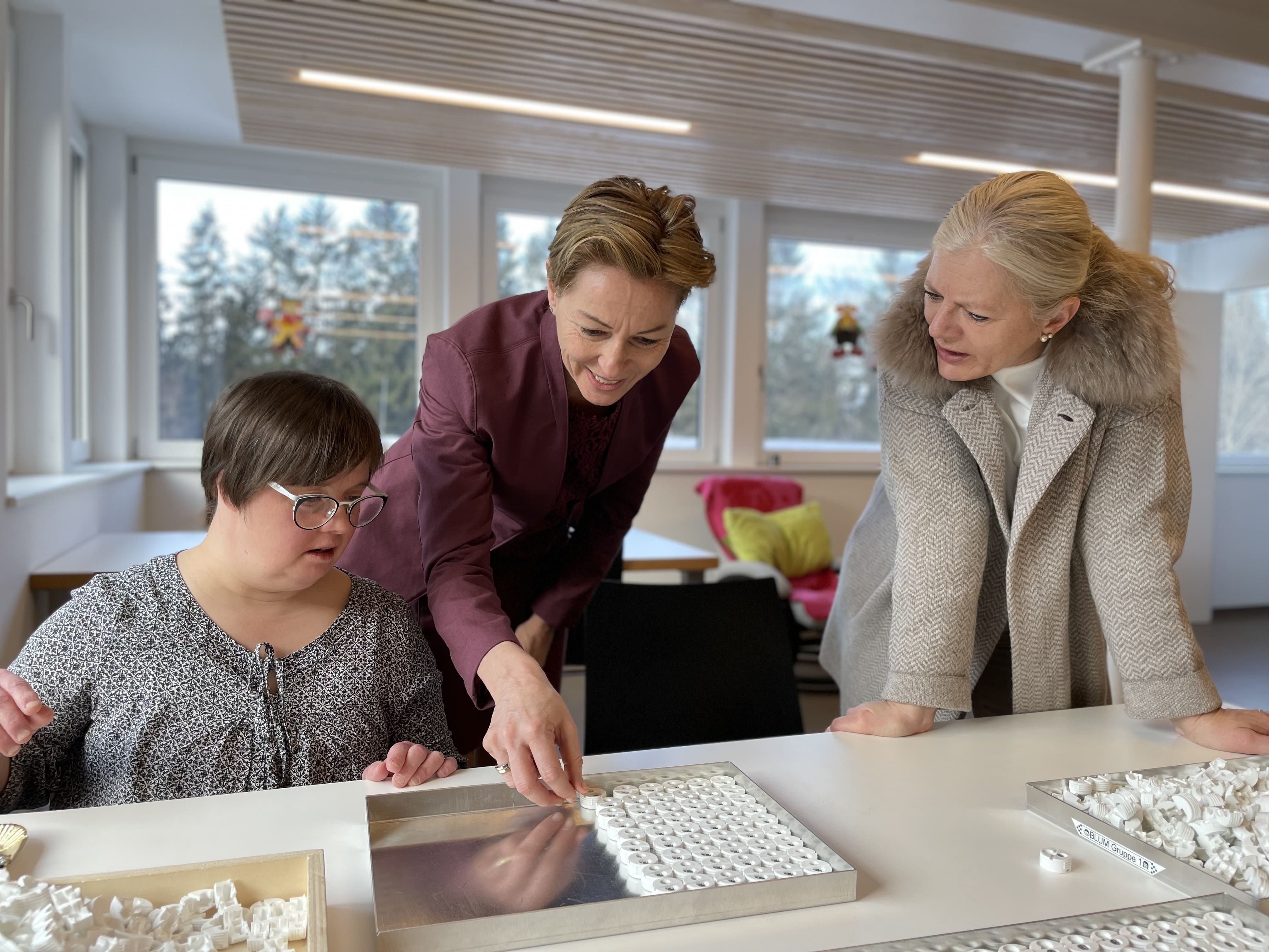 v.li.: Werkstatt-Sprecherin Sandra Mayer erklärt Landesrätin Martina Rüscher und Geschäftsführerin Michaela Wagner-Braito die Auftragsarbeit.