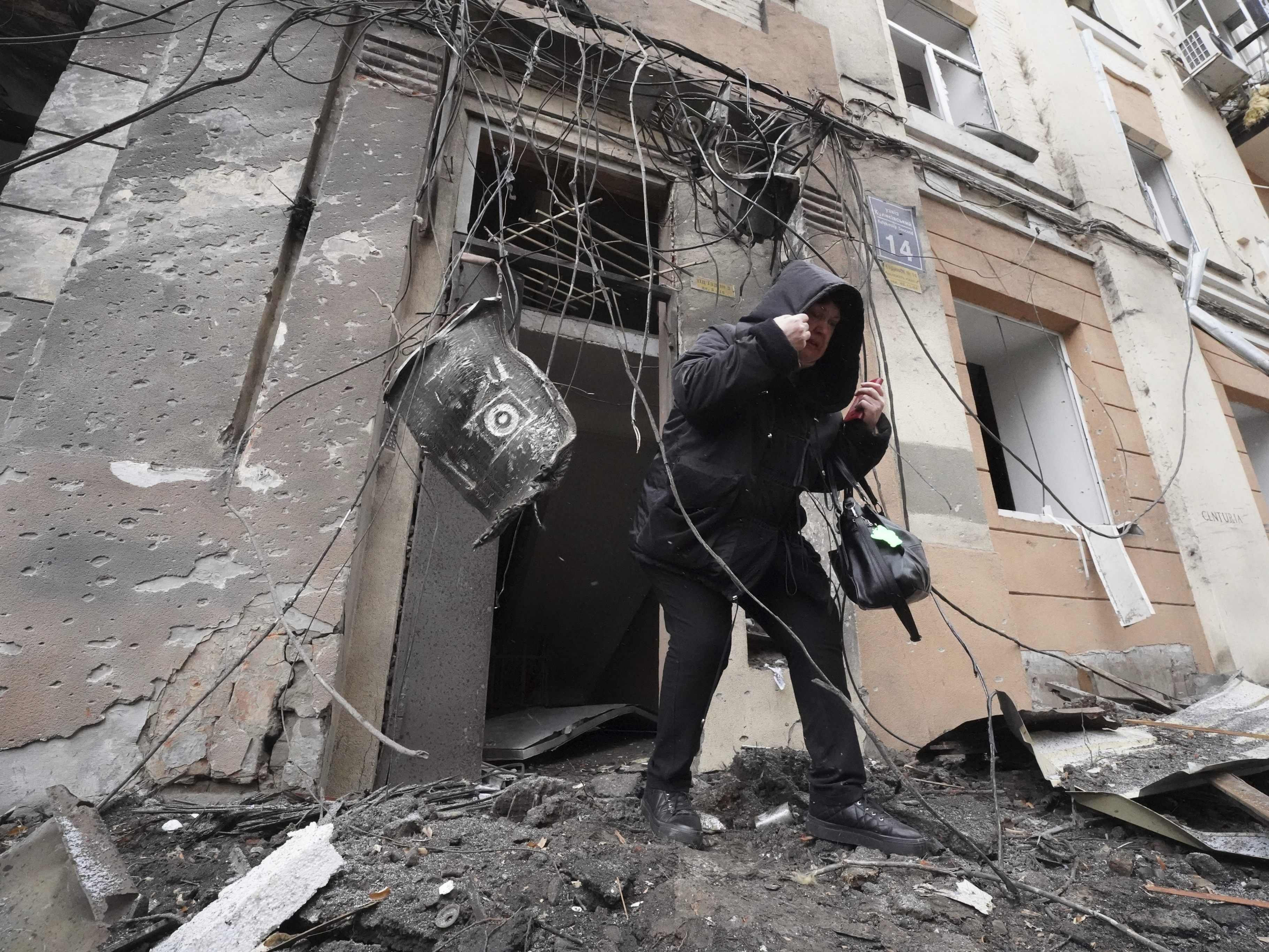 Ein Mann vor einem zerbombten haus in der Ukraine.