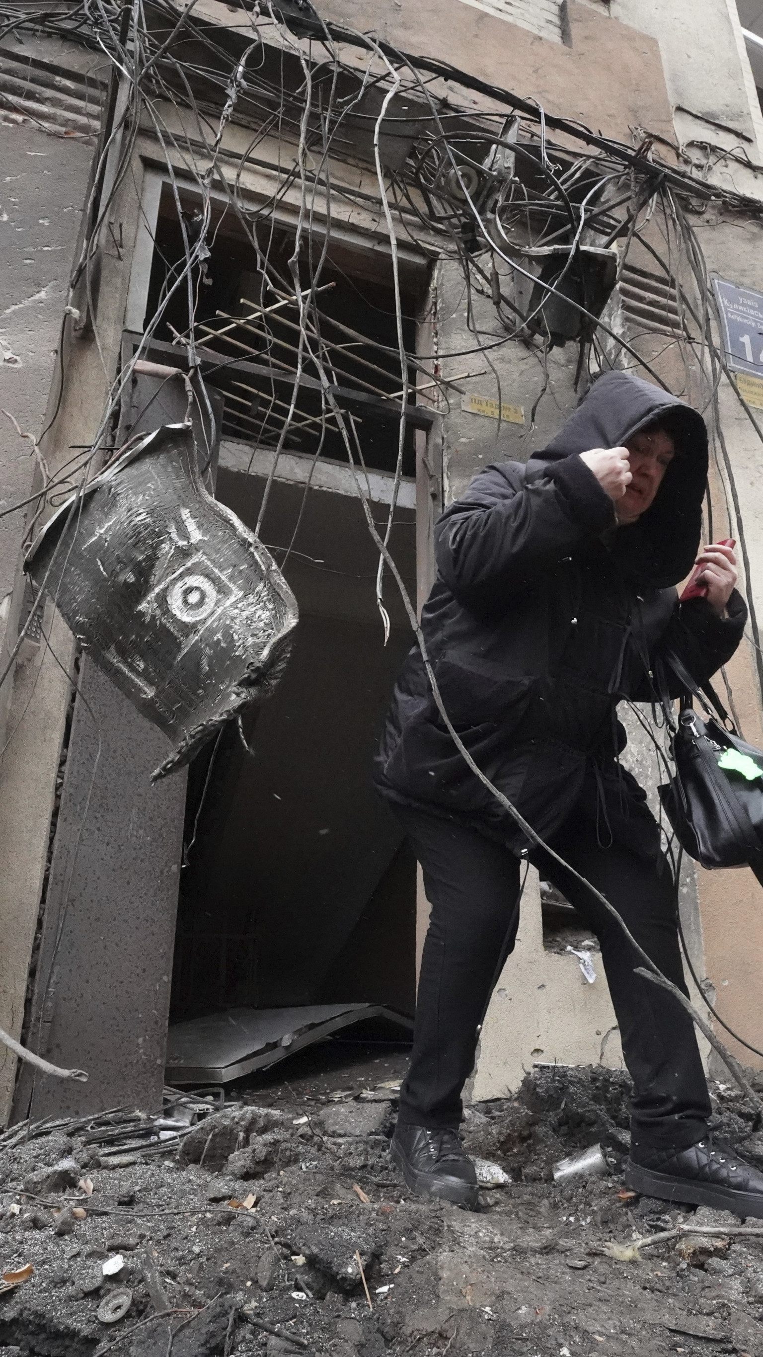 Ein Mann vor einem zerbombten haus in der Ukraine.