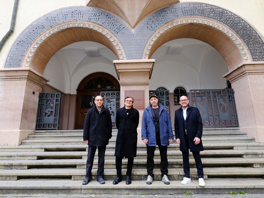 Kulturstadtrat Michael Rauth, Künstler Marbod Fritsch, Schuldirektor Bernhard Posch und Bürgermeister Michael Ritsch vor dem Schulgebäude
