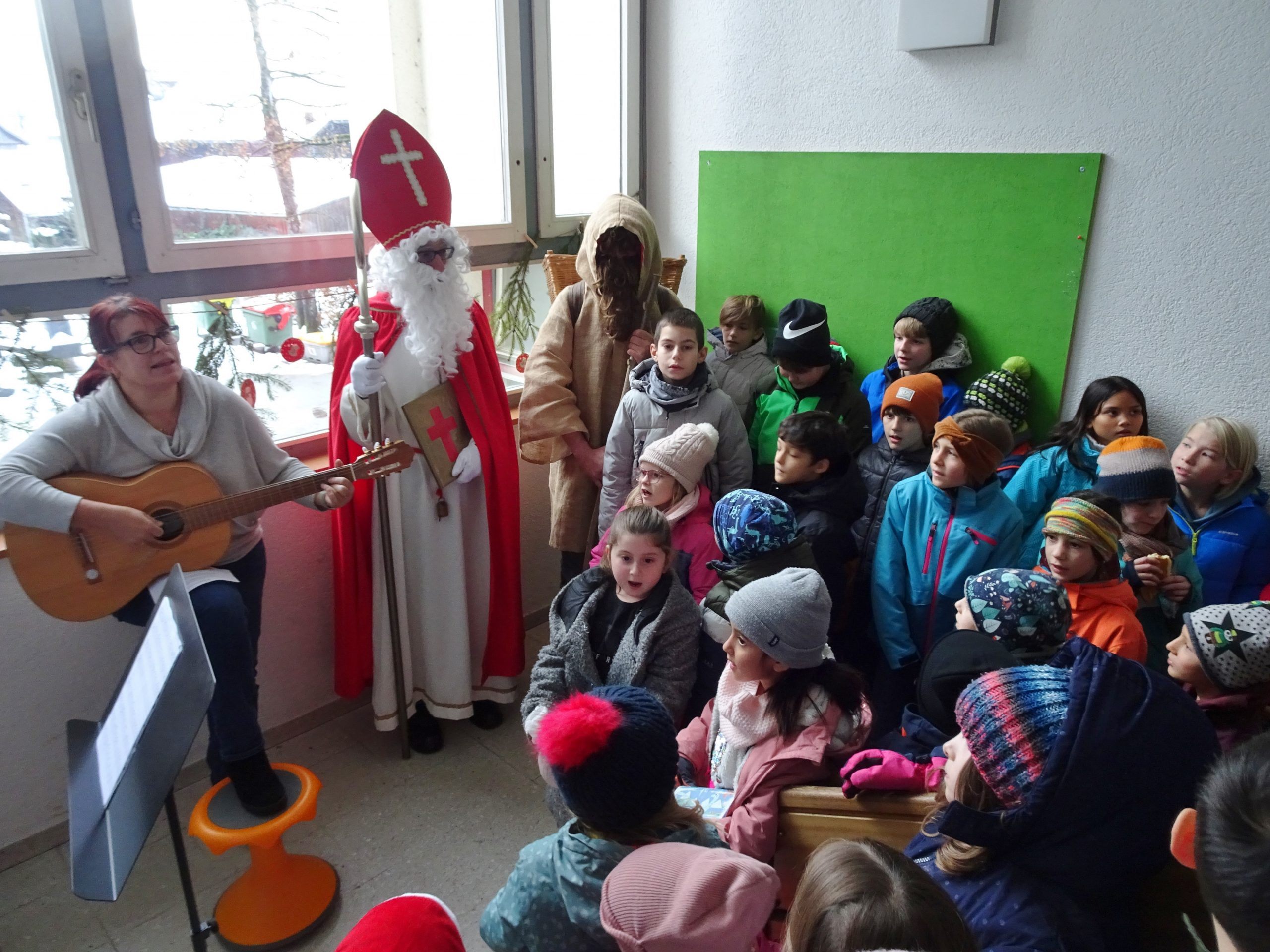 Das ganze Schultreppenhaus war mit kleinen Sängerinnen und Sängern gefüllt, um dem Nikolaus und dem Knecht Ruprecht ein Ständchen zu singen. Das ganze Schultreppenhaus war mit kleinen Sängerinnen und Sängern gefüllt, um dem Nikolaus und dem Knecht Ruprecht ein Ständchen zu singen.
