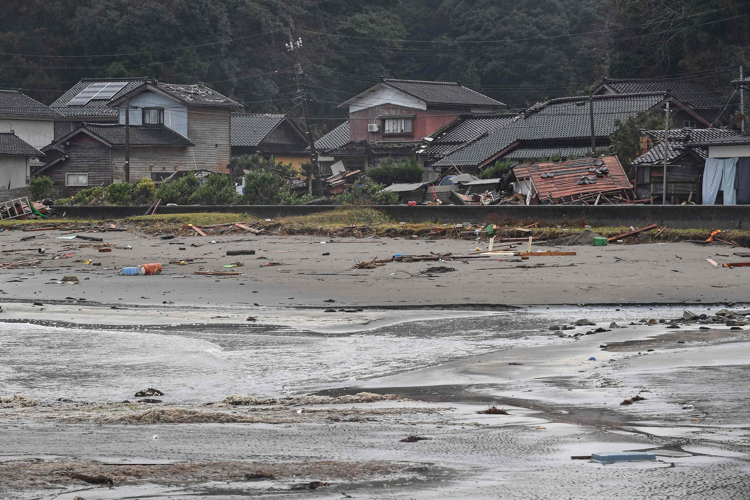 Dieses Bild zeigt Trümmer an einem Strand neben beschädigten Häusern in einem von Tsunamiwellen betroffenen Gebiet in der Stadt Misaki in der Stadt Suzu in der Präfektur Ishikawa am 7. Januar 2024