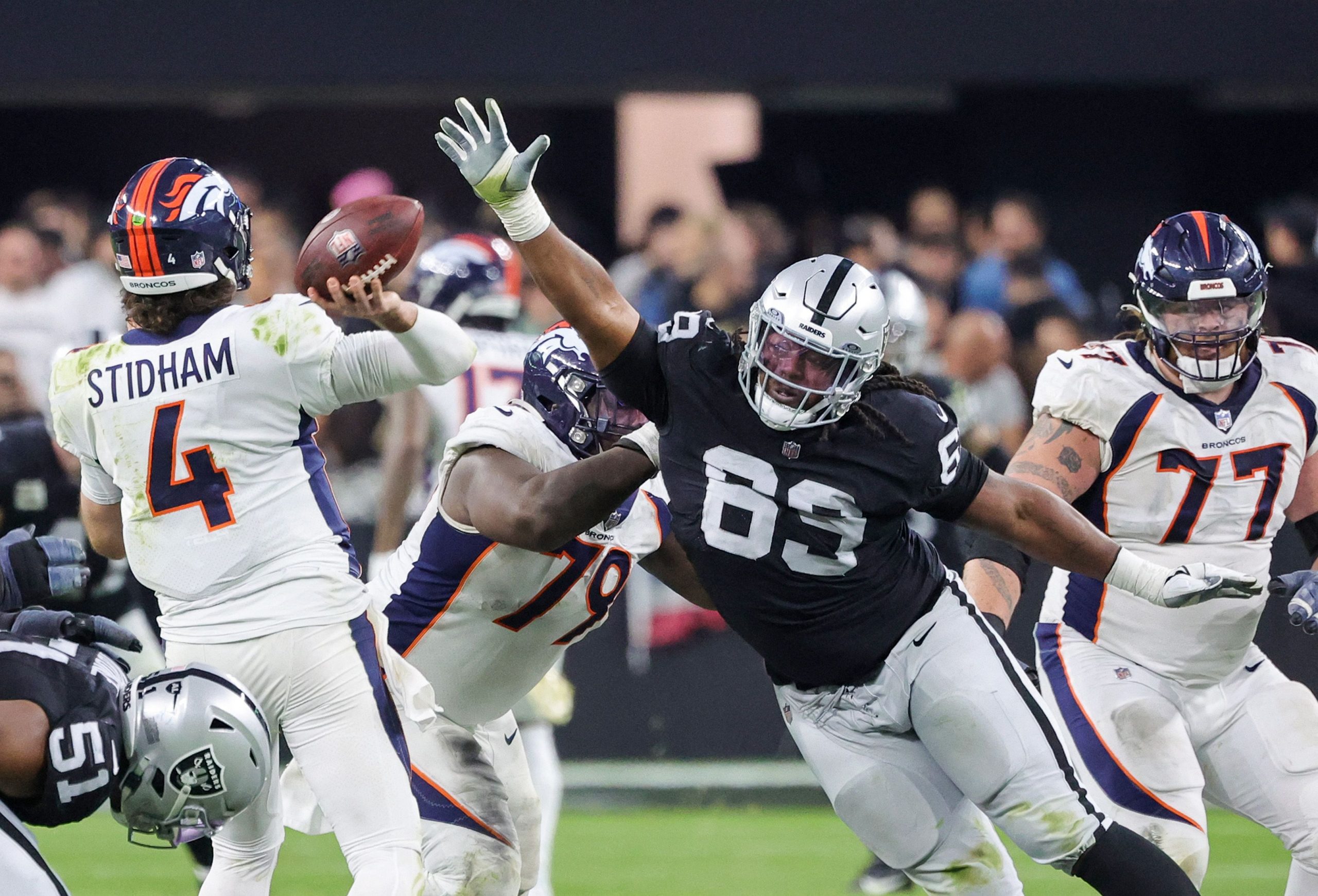 Quarterback Jarrett Stidham #4 der Denver Broncos wirft eine Interception unter dem Druck von Defensive Tackle Adam Butler #69 der Las Vegas Raiders gegen Ende des vierten Viertels ihres Spiels im Allegiant Stadium am 7. Januar 2024 in Las Vegas, Nevada