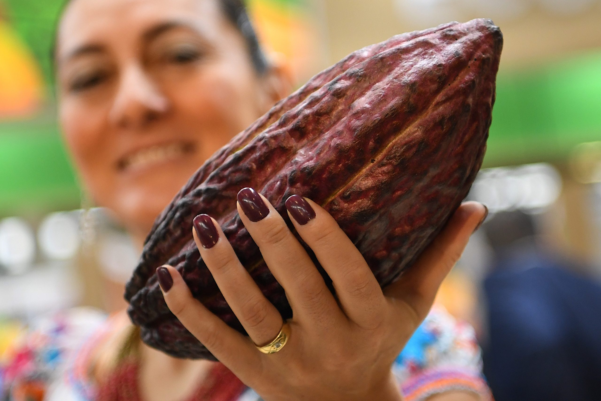 Eine Frau hält eine Kakaofrucht an einem Stand auf der Fruit Logistica 