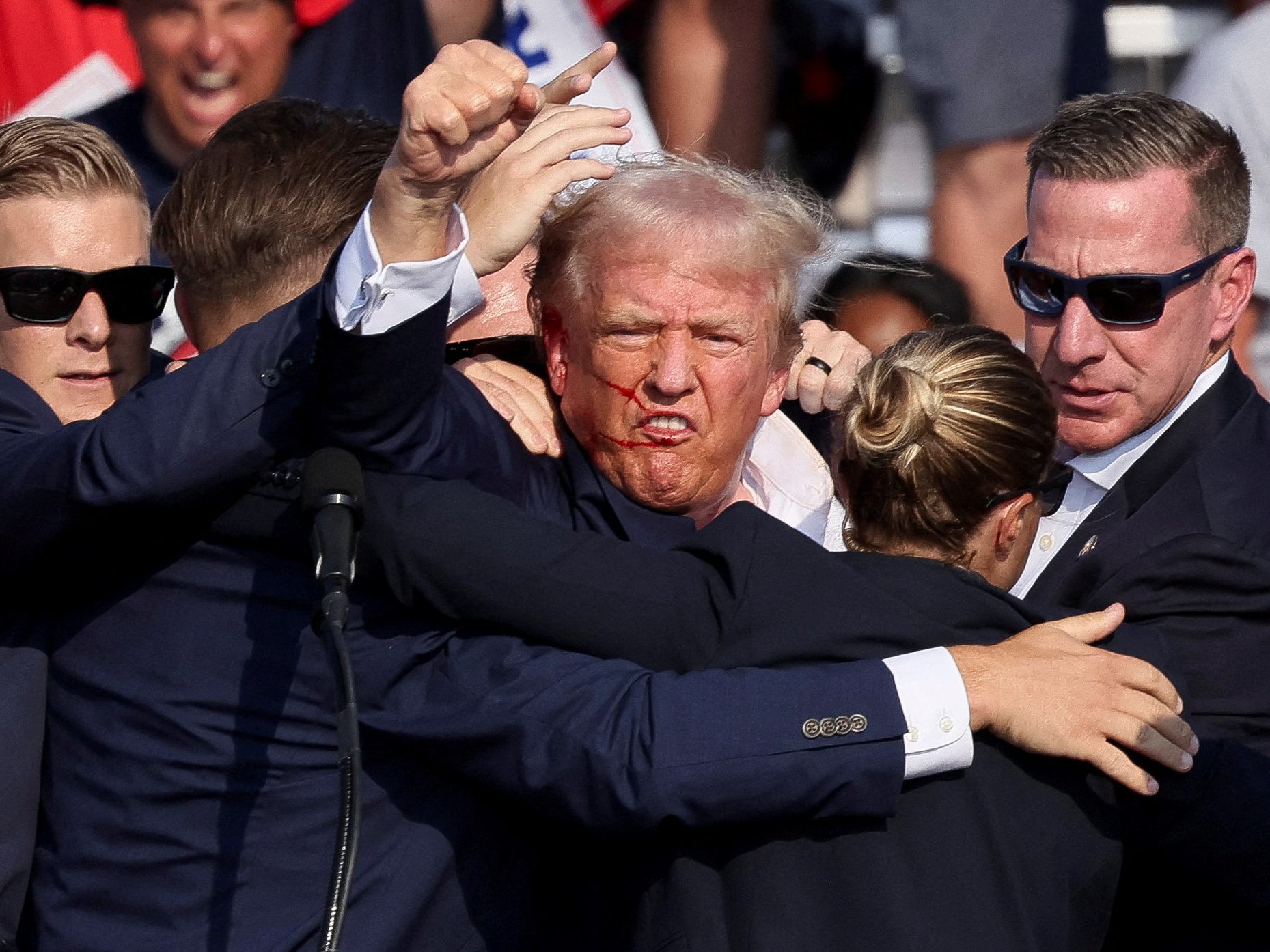 Agenten des Secret Service umringen den verletzten Ex-Präsident Trump. Agenten des Secret Service umringen den verletzten Ex-Präsident Trump.