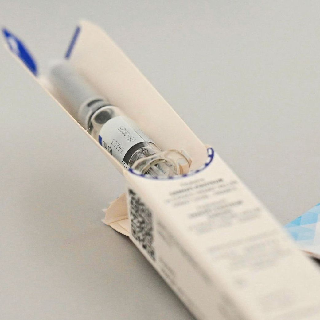 Ein Gesundheitsmitarbeiter trägt nach einer Grippeimpfung in einem Impfzentrum die Impfung in ein Heft ein.