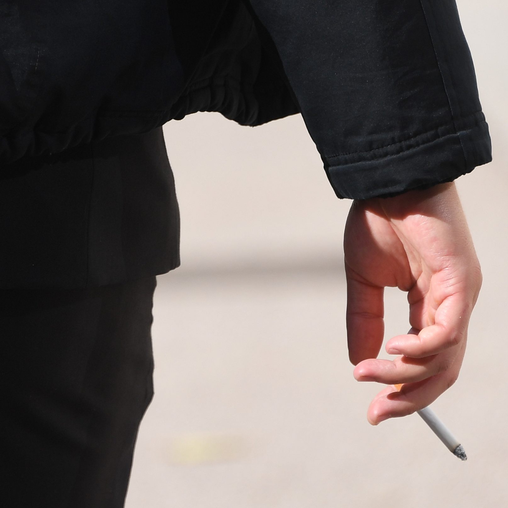 Eine Person hält eine Zigarette in der Hand.