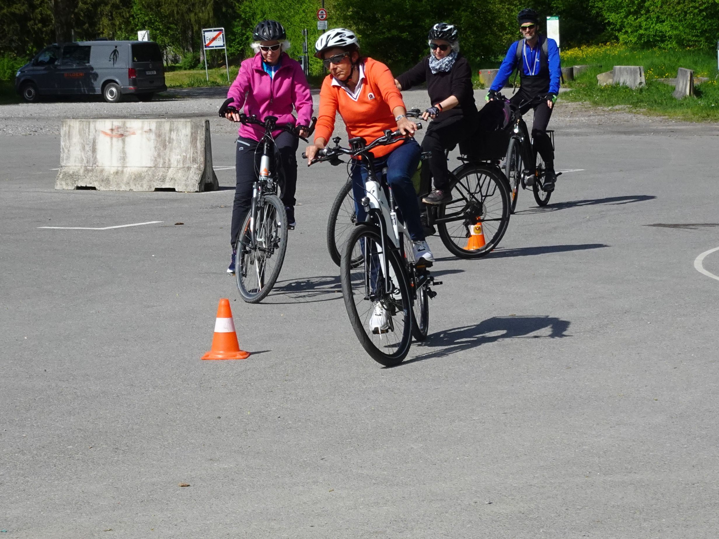 Seniorinnen und Senioren trainieren die richtige Technik für das Fahren mit einem E-Bike.