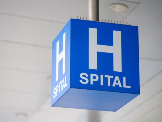 Auf dem Bild sieht man einen typischen Würfel beim Eingangsbereich eines Spitals. Auf dem Würfel steht "Spital".
