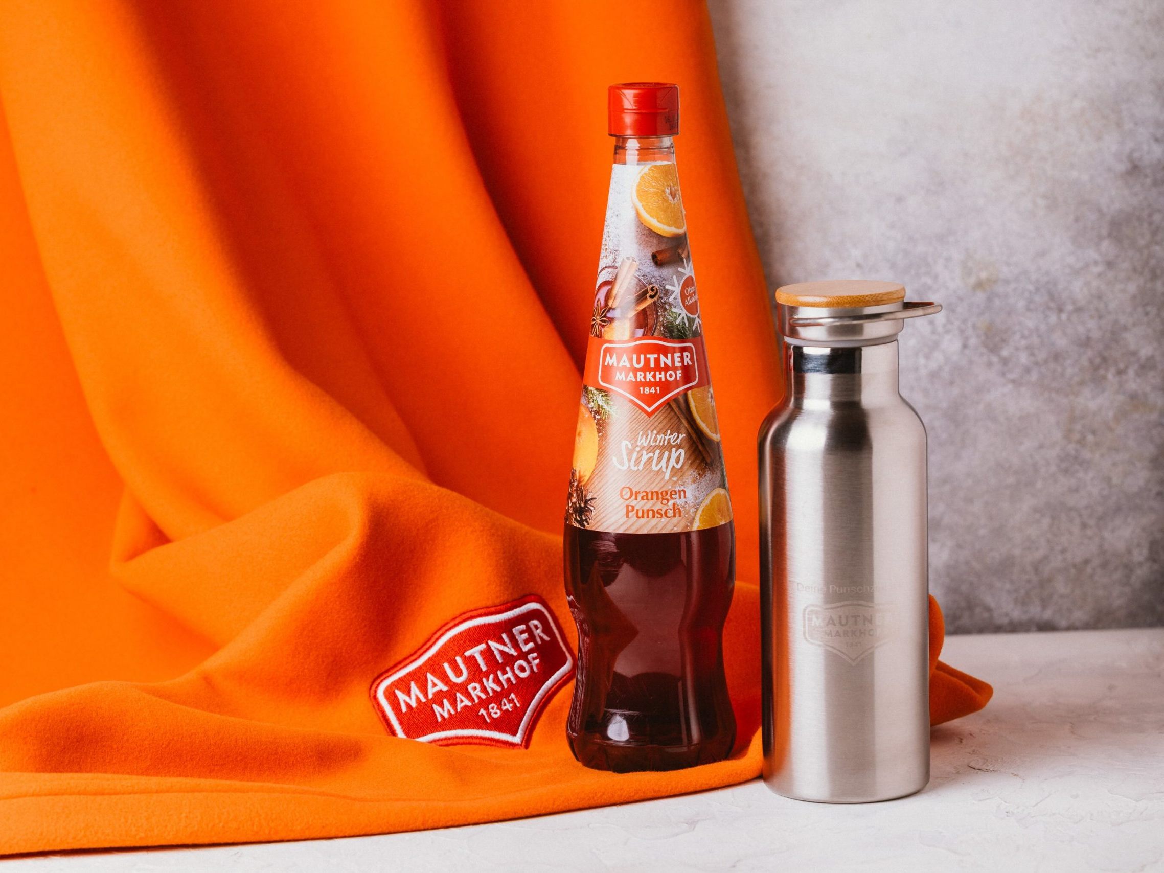 Gewinnt Winterzauber-Pakete mit dem Orangenpunsch-Sirup von Mautner Markhof samt kuscheliger Fleece-Decke und Thermosflasche.