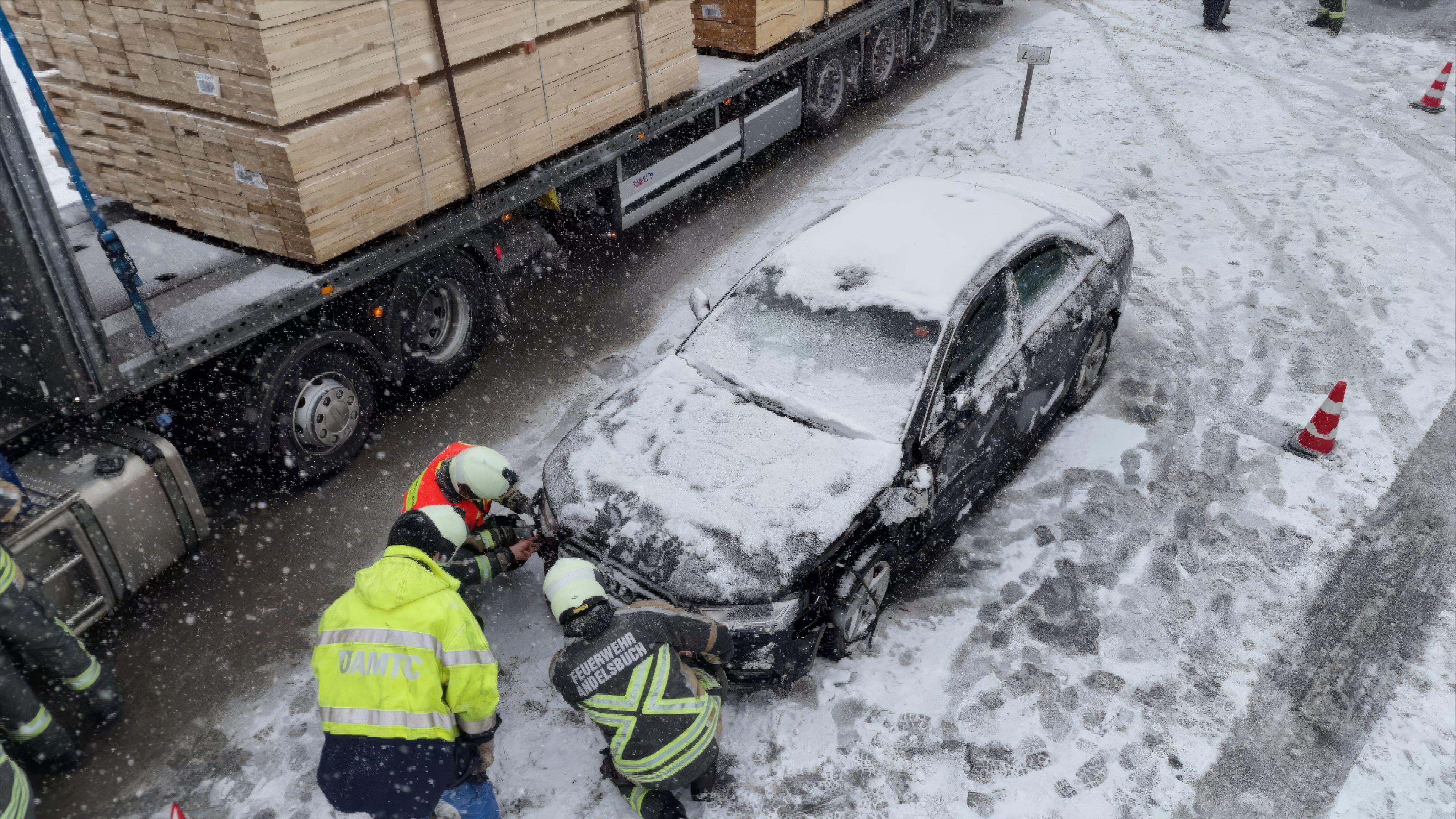 Während der Schneefall andauert, bergen Einsatzkräfte das schwer beschädigte Auto.