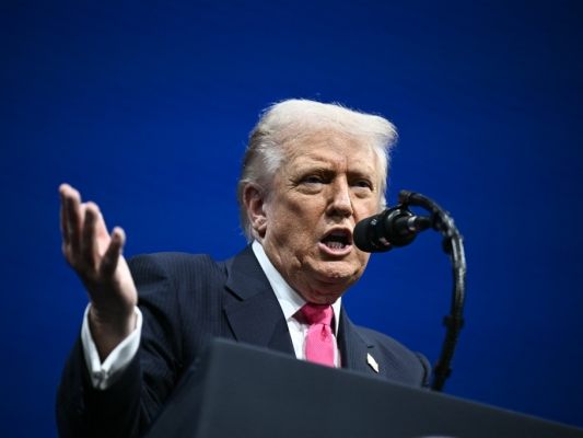 Auf dem Bild sieht man US-Präsident Donald Trump. Er spricht in ein Mikrofon.