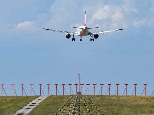 Auf dem Bild sieht man ein Flugzeug fliegen beim Flughafen Wien-Schwechat.