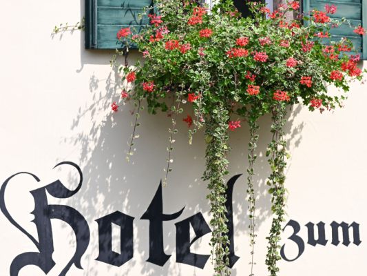 Auf dem Bild sieht man ein Hotel und ein Hotelfenster mit Blumen.