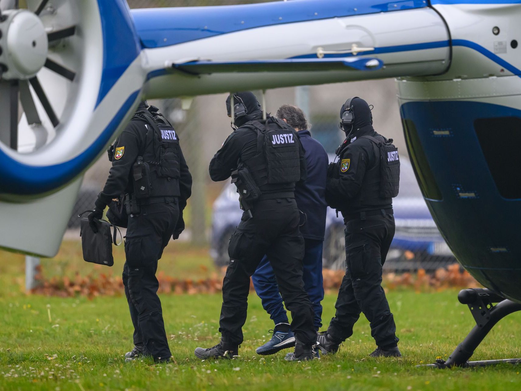 Taleb A. wird von Justizpersonal nach der Landung im Hubscharuber in Magdeburg zur Fahrzeugkolonne geführt.