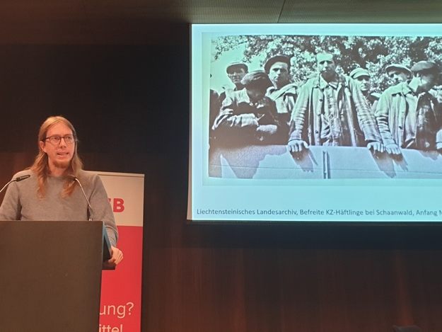 Assistenzprofessor Dr. Nikolaus Hagen präsentiert ein Foto, das befreite KZ-Häftlinge auf ihrem Weg nach Liechtenstein zeigt.