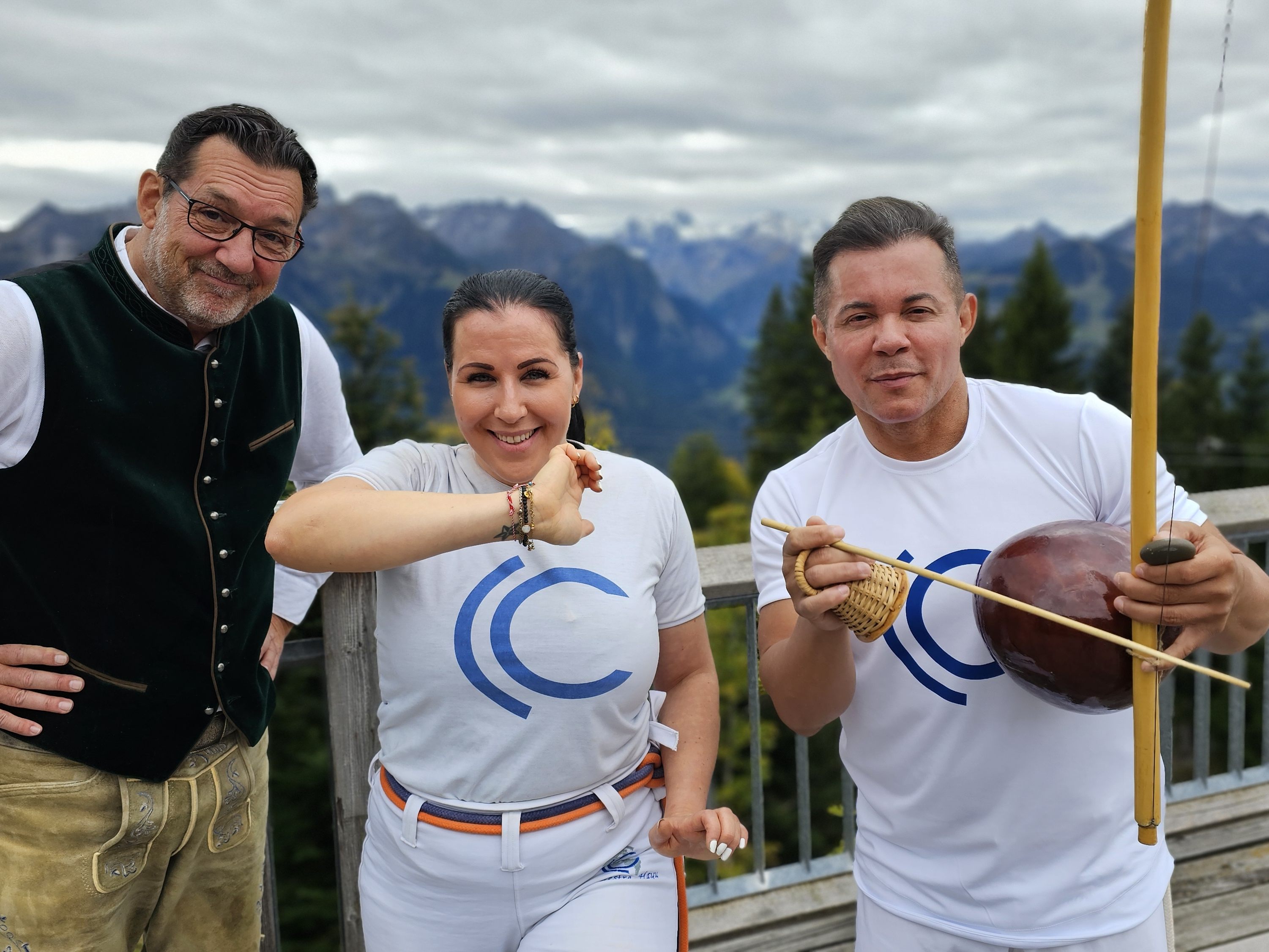 Die Capoeirista Christina Tschofen (mi) und ihr Mestre Hayu (re) zeigen Andreas Seeburger (li) nach der Muttersberg-Fernsehgondelfahrt, auf der Alpengasthof-Panoramaterrasse ihre Sportart in Aktion.