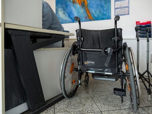 Auf dem Bild sieht man einen Rollstuhl in einem Büro.