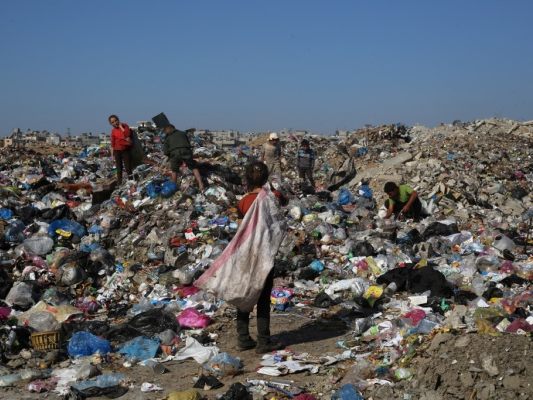Auf dem Bild sieht man Kinder in einem Müll- und Schuttberg wühlen.